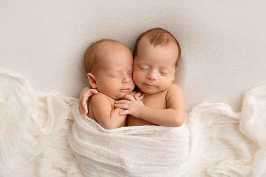 Two newborn babies wrapped together in soft white blanket – blog cover for posing tips in maternity and newborn photography