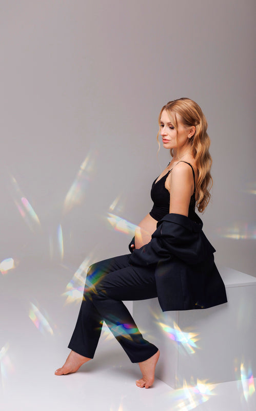 Woman in black outfit sitting on a white box with colorful light effects