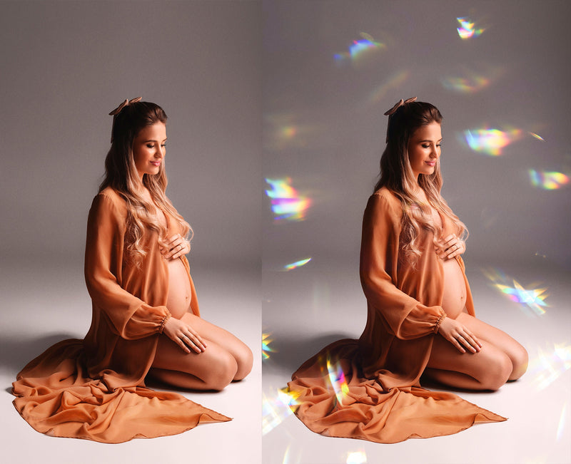Pregnant woman in a flowing dress kneeling on a gray background with rainbow light effects.