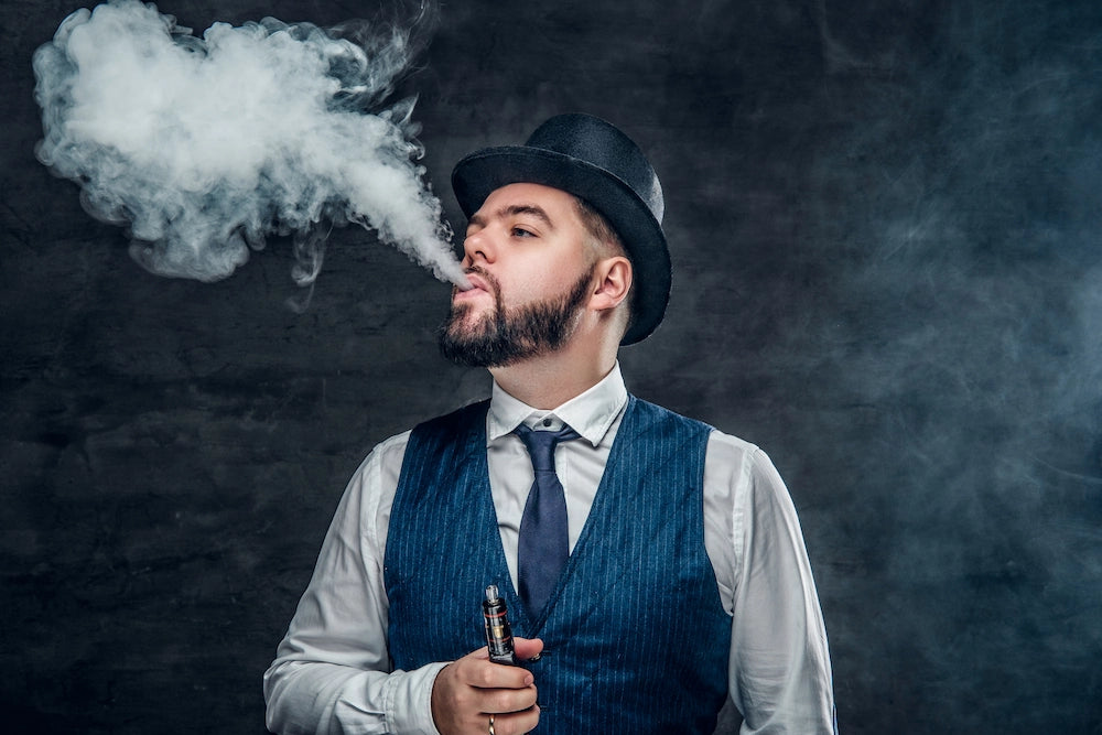 Man in vintage attire exhaling vape smoke against a dark background